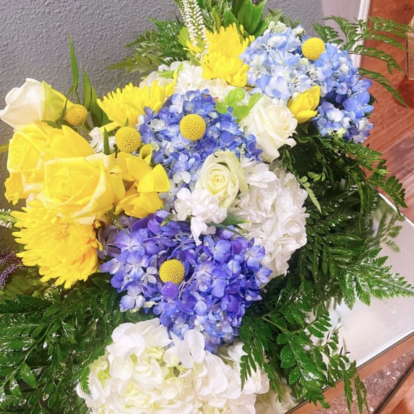 Bouquet of yellow and white roses with blue hydrangeas and yellow mums