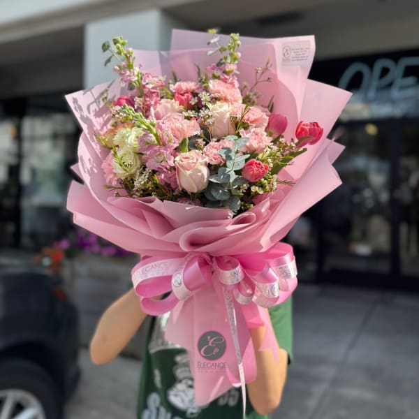 Pink bouquet of roses, tulips, and carnations wrapped in pink paper