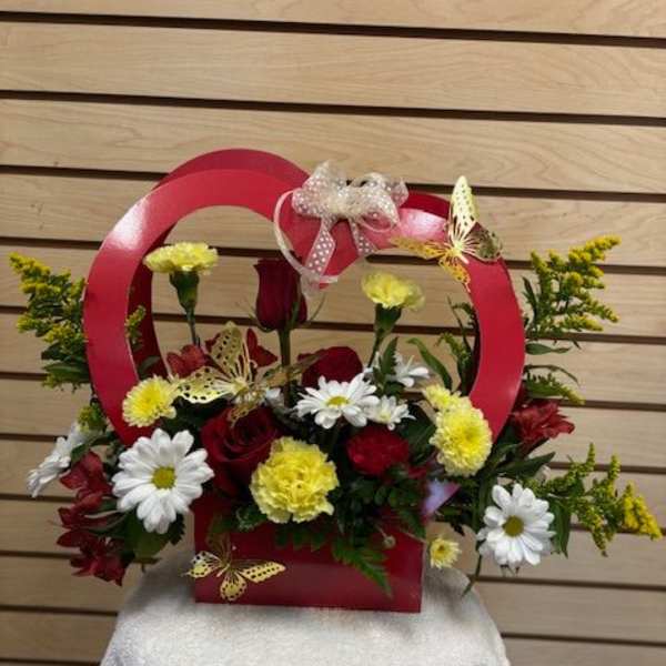Red basket arrangement with red roses, white daisies, and yellow carnations