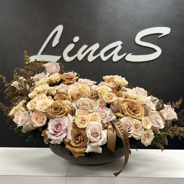 Large bouquet of pale roses in a low dark bowl