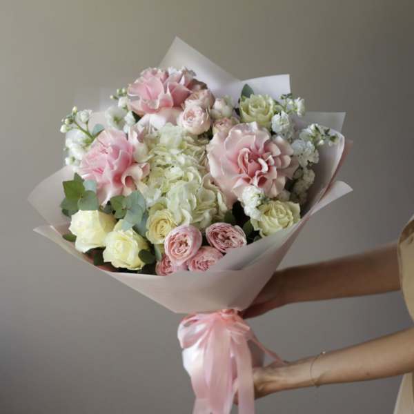 Bouquet of pink and white roses wrapped in pale paper
