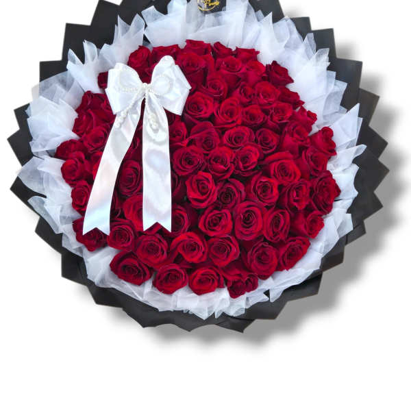 Large bouquet of red roses wrapped in black and white paper with a white bow