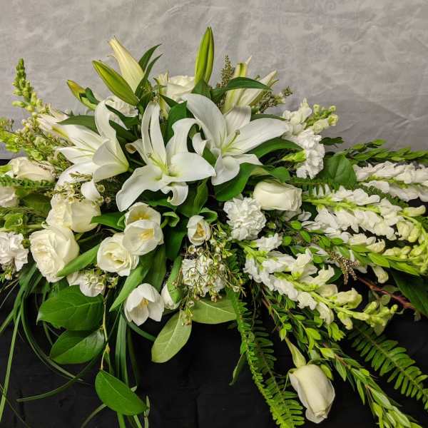 White lilies and roses arranged in a low, elongated spray