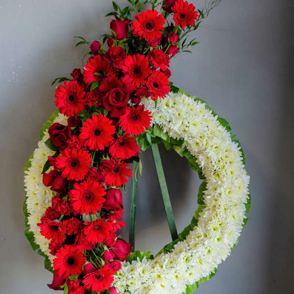 Standing floral wreath with red and white flowers on a green easel