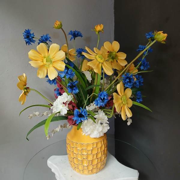 Yellow and blue flowers arranged in a patterned vase
