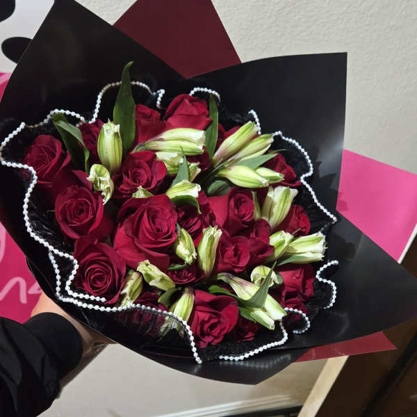 Bouquet of red roses and white lily buds wrapped in black paper