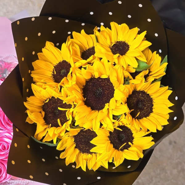 Bouquet of yellow sunflowers wrapped in black polka-dot paper