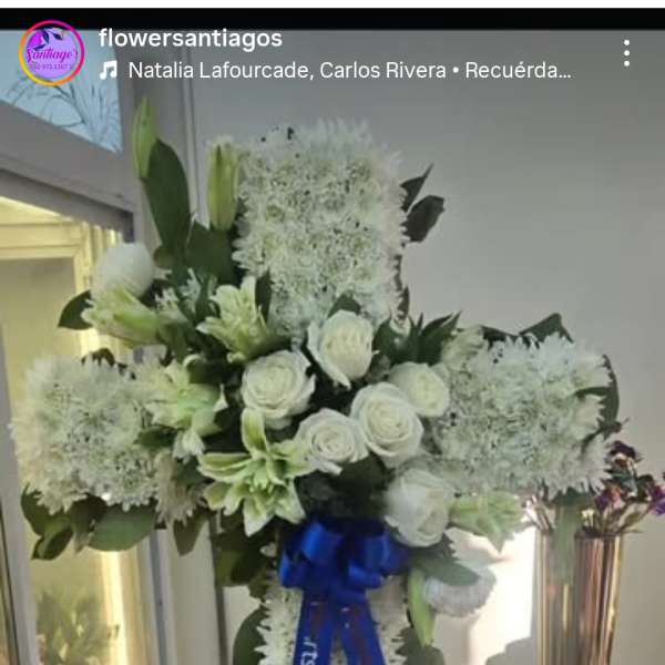 White floral standing spray on an easel with a blue ribbon
