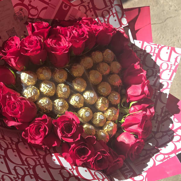 Bouquet of red roses surrounding gold-wrapped chocolates