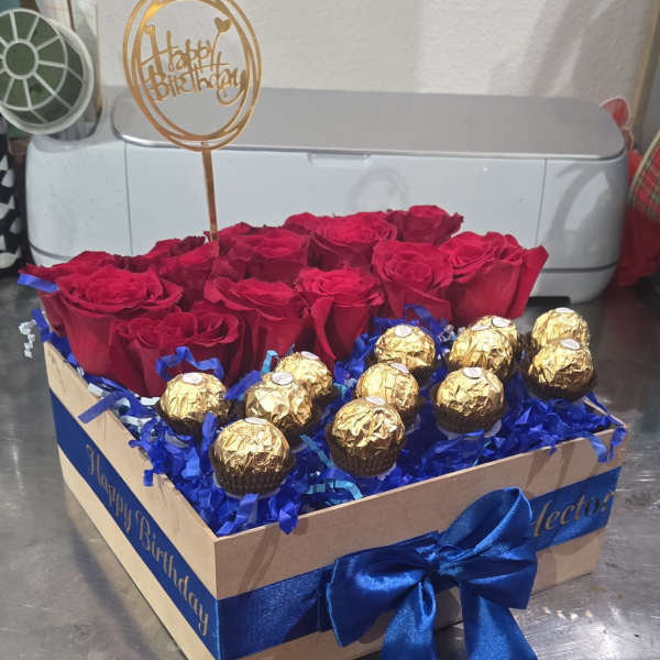 Red roses and gold-wrapped chocolates in a gift box with a birthday topper