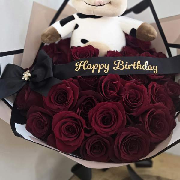 Bouquet of red roses with a plush cow and Happy Birthday ribbon