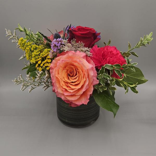 Mixed flower arrangement in a black vase with roses and carnations