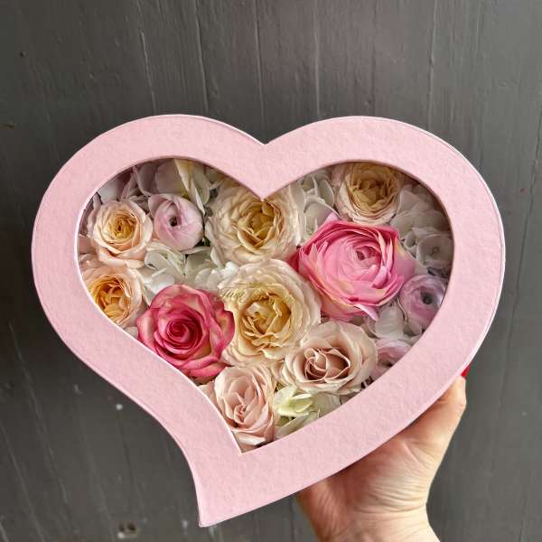 Heart-shaped pink box filled with pastel roses and hydrangea petals