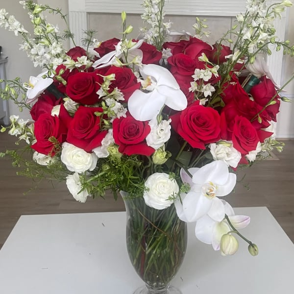Red roses and white orchids arranged in a clear glass vase