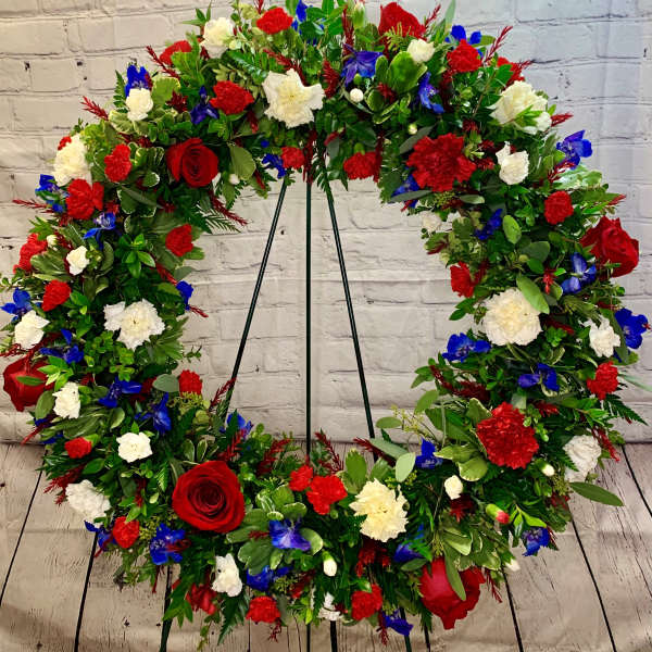 Large floral wreath with red, white, and blue flowers on a stand