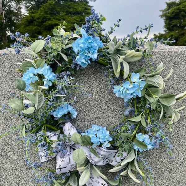 Blue floral wreath with ribbon on a gray stone surface