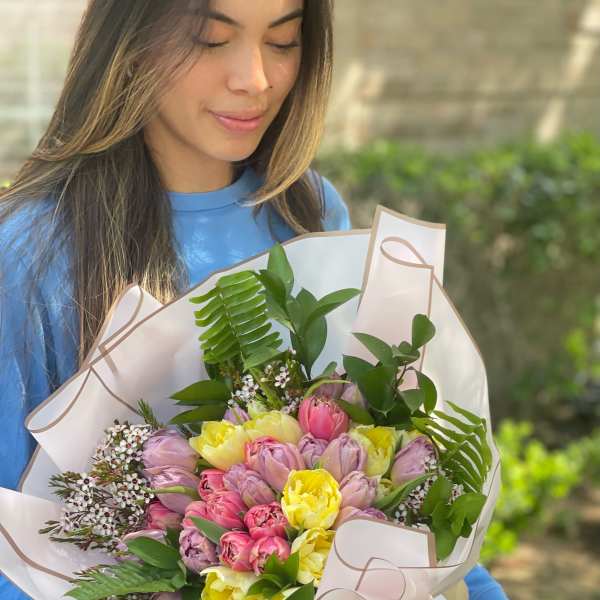 Woman holding a pastel bouquet of tulips wrapped in white paper