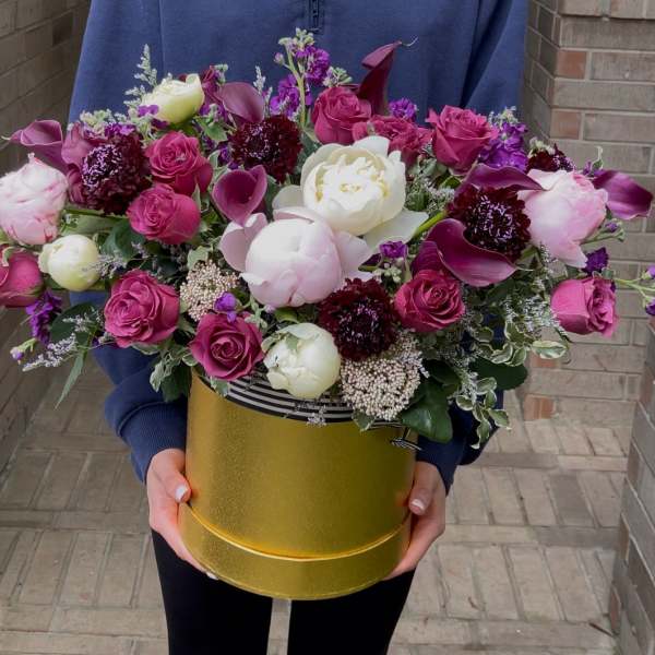 Large bouquet of pink and white flowers in a gold hatbox