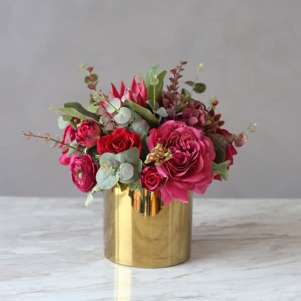 Pink and red roses arranged in a gold vase