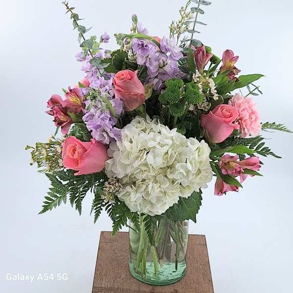 Mixed bouquet of pink roses, purple stock and white hydrangea in a clear glass vase