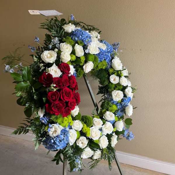 Large standing floral wreath with red, white, and blue flowers on an easel
