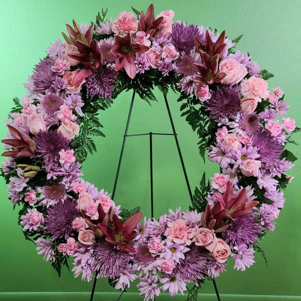 Large pink and purple floral wreath on a stand