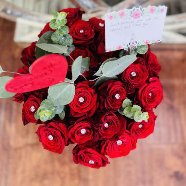 Heart-shaped bouquet of red roses with a small note card