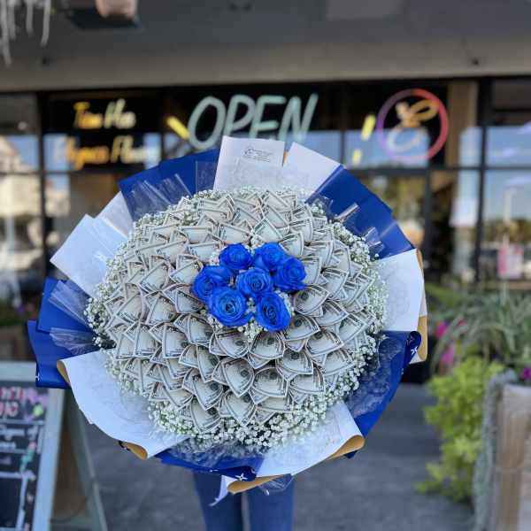 Bouquet of blue roses surrounded by folded dollar bills