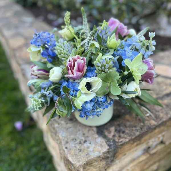 Blue and pink mixed flower arrangement in a white vase