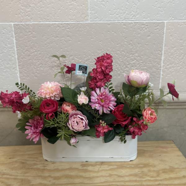 Pink and red mixed flower arrangement in a white container