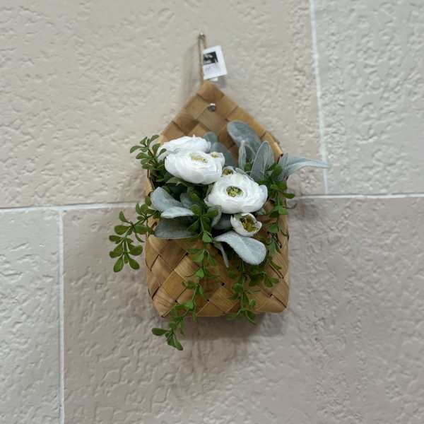 White flowers and greenery in a woven wall basket