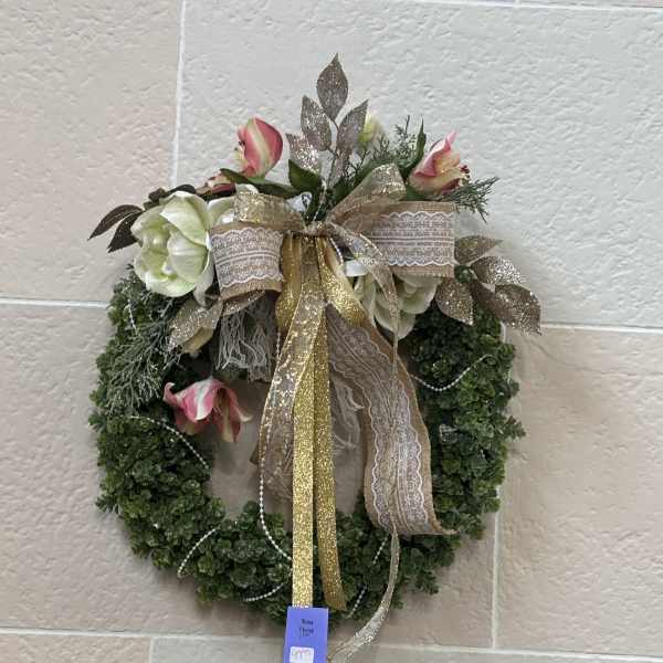 Floral wreath with pink and white flowers and a gold ribbon bow