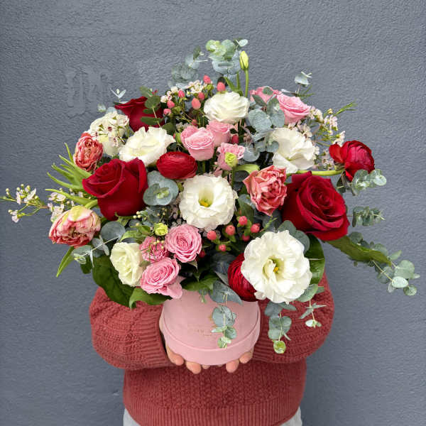 Bouquet of red, pink, and white roses in a pink hat box