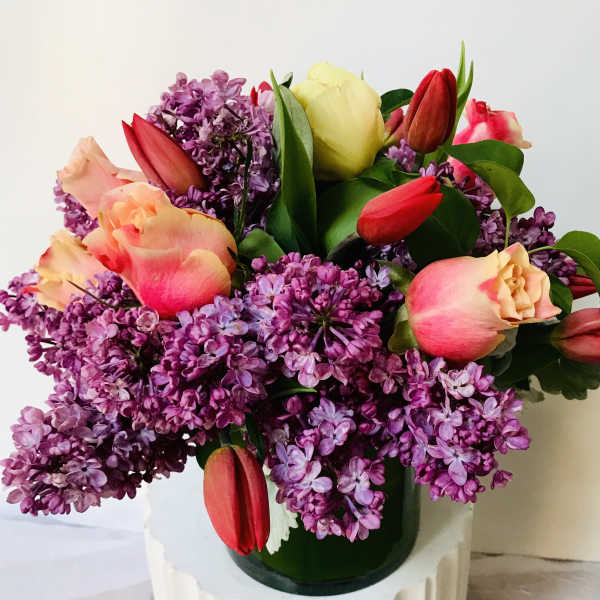 Bouquet of purple lilacs and pink tulips in a glass vase