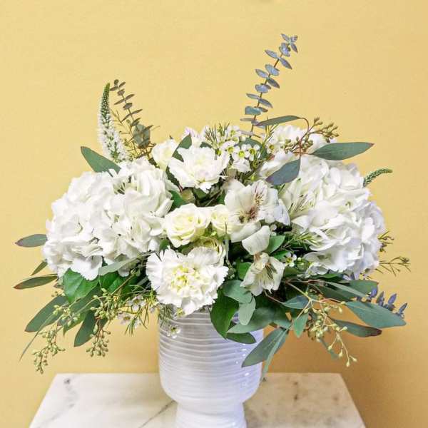 White floral arrangement in a white vase with eucalyptus