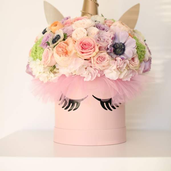 Pastel flower arrangement in a pink unicorn box with a gold horn