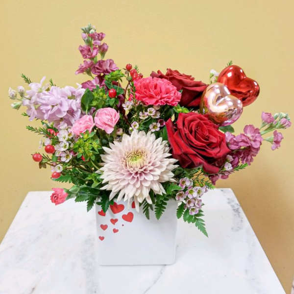 Mixed bouquet with red roses, pink blooms, and heart balloons in a white box