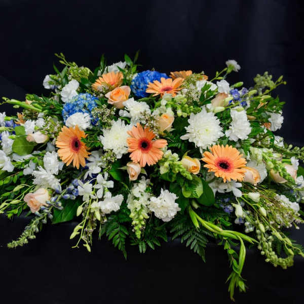 Low floral spray with peach gerberas, white blooms, and blue hydrangeas