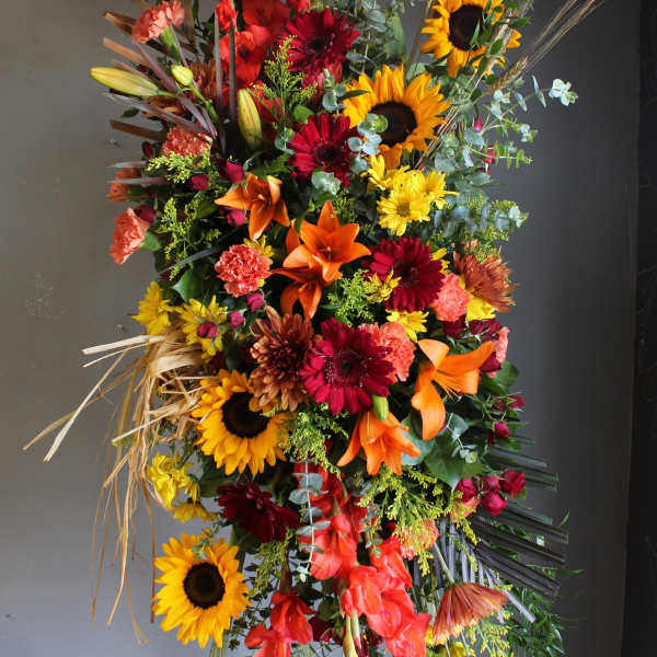 Tall floral spray with sunflowers, lilies, and red gerbera daisies