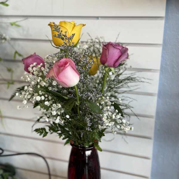 Mixed roses in a red glass vase with baby's breath