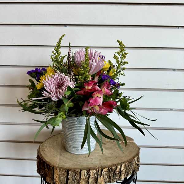 Mixed pink, yellow, and purple flowers in a metal bucket