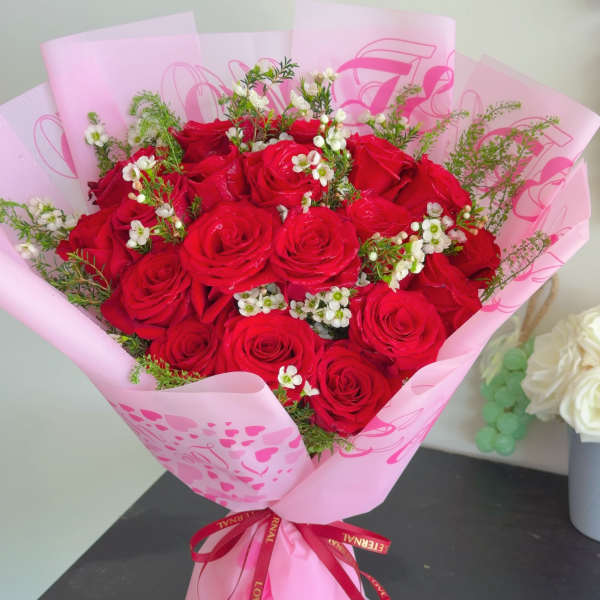 Bouquet of red roses wrapped in pink paper with a ribbon