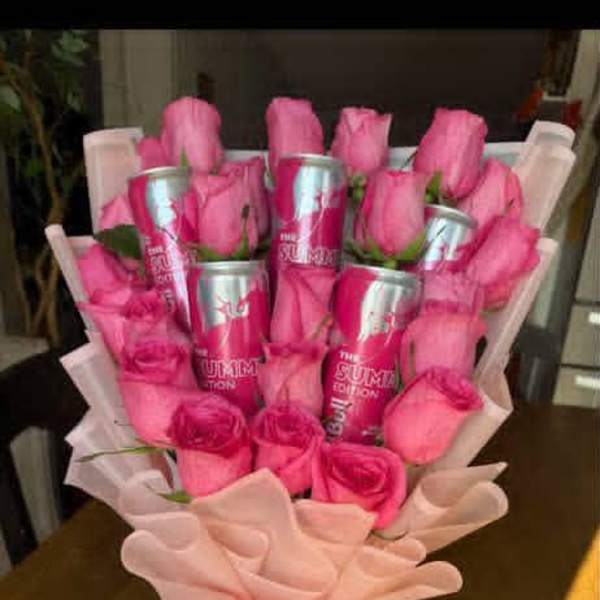 Pink roses arranged with pink cans in a wrapped bouquet