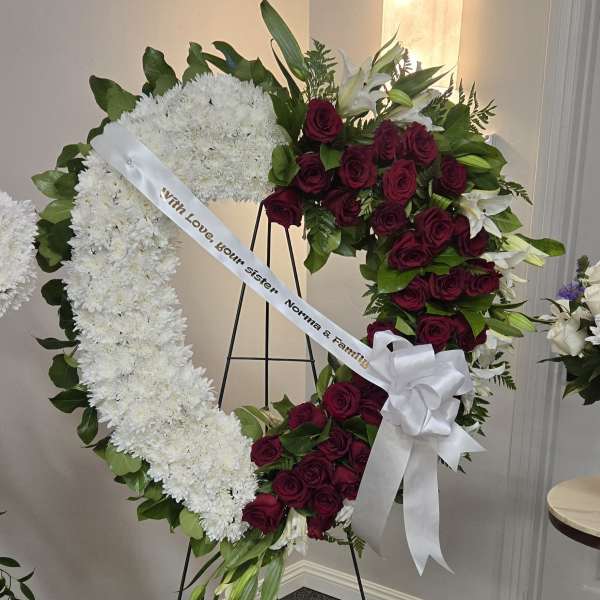 Heart-shaped funeral wreath of white chrysanthemums and red roses on an easel