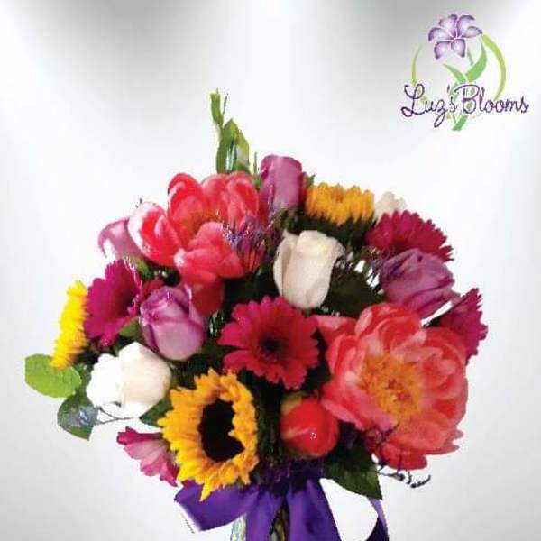 Colorful mixed bouquet in a glass vase with a purple ribbon