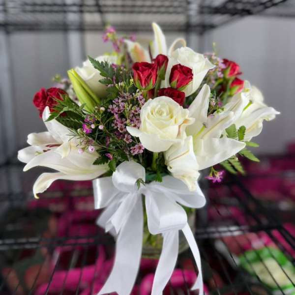 Bouquet of white lilies and red roses with a white ribbon