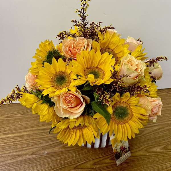 Sunflower and peach rose bouquet in a white vase