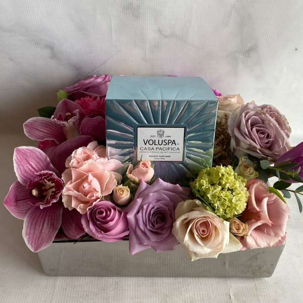 Floral gift box with roses, orchids, and a candle in the center
