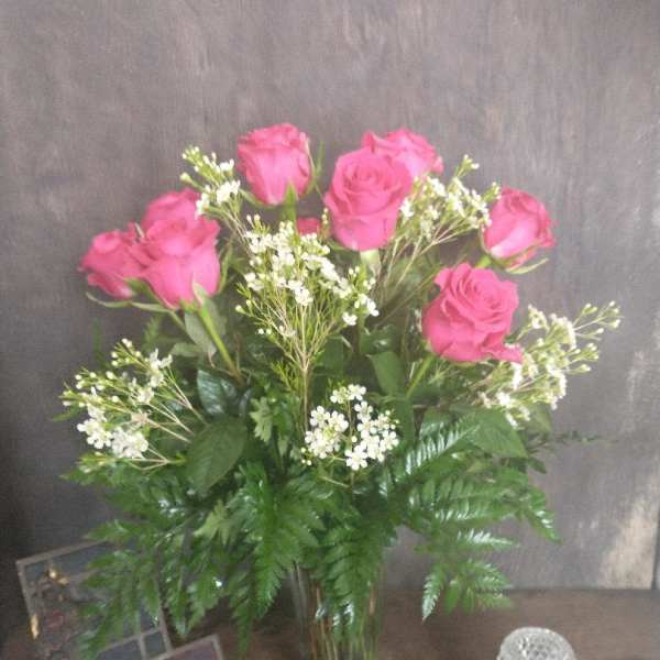 Pink roses in a glass vase with white filler flowers