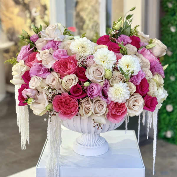 Large pink and white rose arrangement in a white pedestal vase